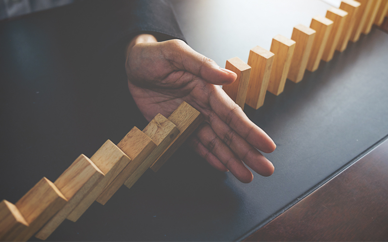Main retenant la chute de domino
